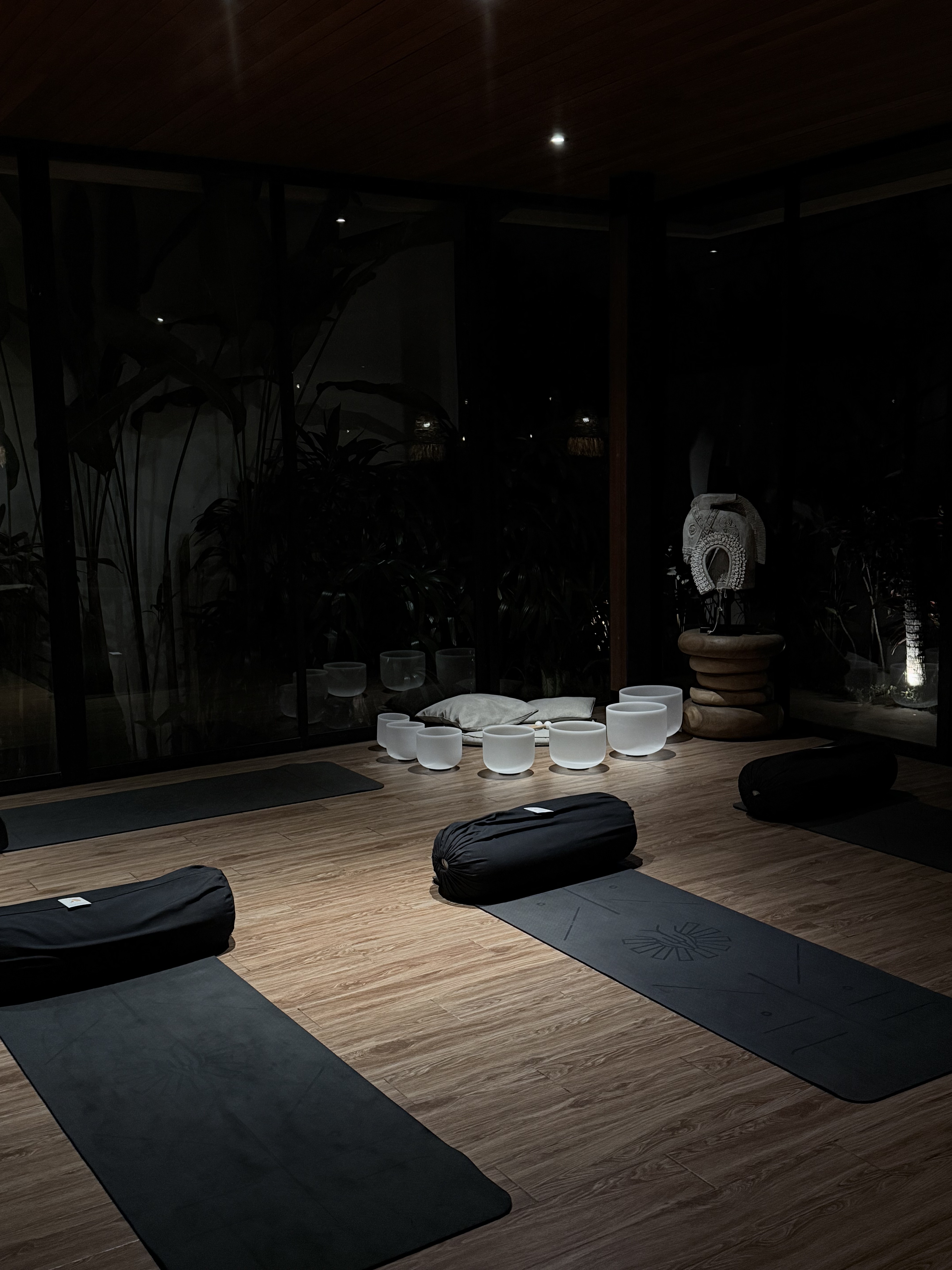 A candle-lit room set for a breathwork journey with crystal sound bowls, mats and bolsters